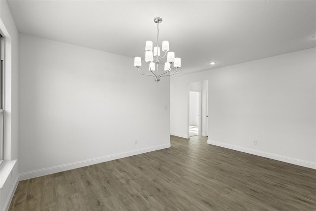 empty room featuring dark hardwood / wood-style floors and an inviting chandelier