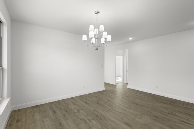 unfurnished room featuring a notable chandelier and dark wood-type flooring