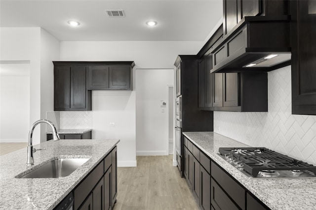 kitchen featuring sink, light hardwood / wood-style flooring, appliances with stainless steel finishes, light stone counters, and custom exhaust hood