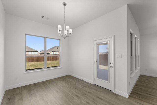 unfurnished dining area featuring a notable chandelier, wood-type flooring, and a wealth of natural light