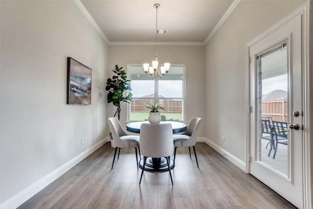 dining room with light hardwood / wood-style flooring, a wealth of natural light, and crown molding