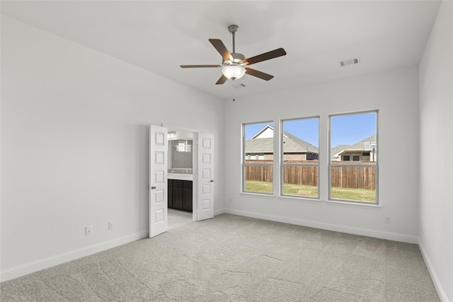 unfurnished bedroom with connected bathroom, light colored carpet, and ceiling fan