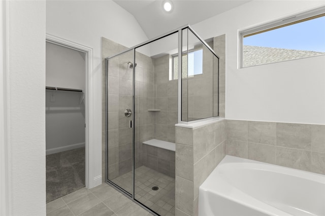 bathroom with independent shower and bath, vaulted ceiling, and tile patterned floors