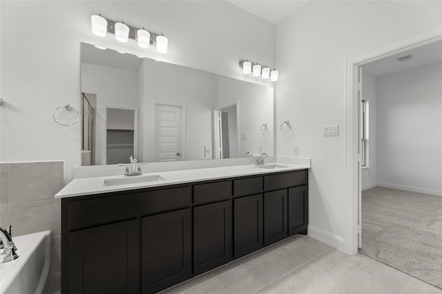 bathroom with a washtub, vanity, and tile patterned floors