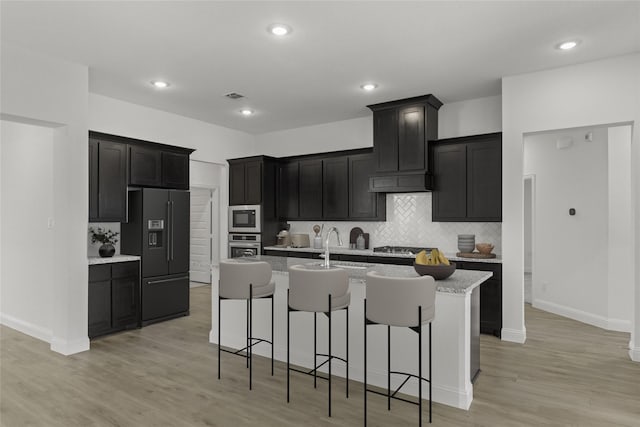 733 Lemmon Ln, Forney, TX 75126 - kitchen featuring dark cabinets, appliances with stainless steel finishes, tasteful backsplash, and a kitchen island with sink