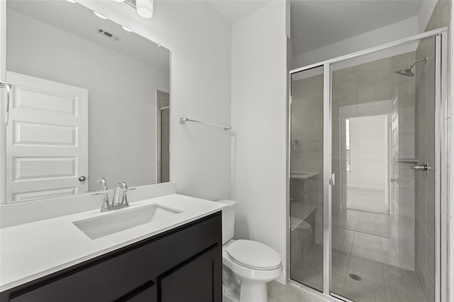 bathroom with tile patterned flooring, vanity, a shower with shower door, and toilet