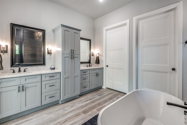 bathroom featuring hardwood / wood-style flooring, vanity, and a tub to relax in