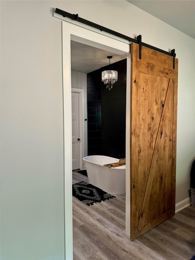 bathroom featuring a washtub, wood-type flooring, and a chandelier