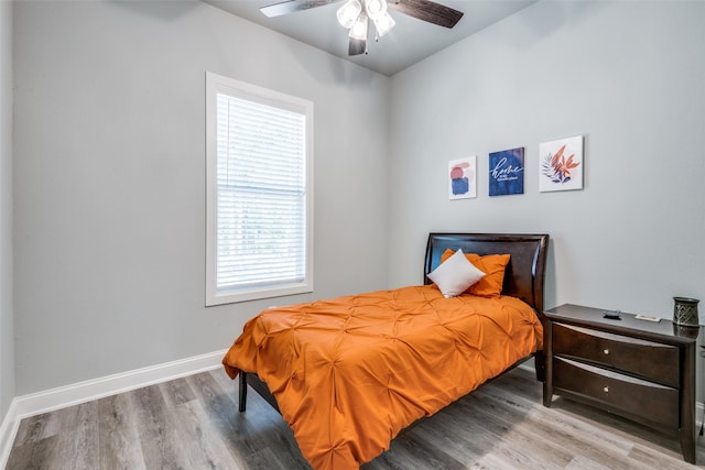 bedroom with multiple windows, ceiling fan, and hardwood / wood-style flooring