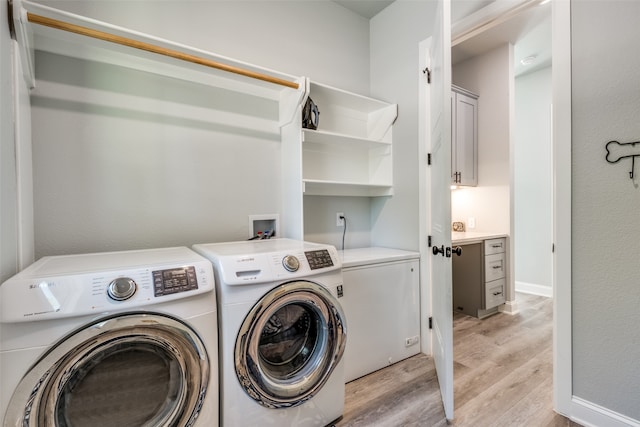 laundry room featuring washing machine and dryer and light hardwood / wood-style flooring