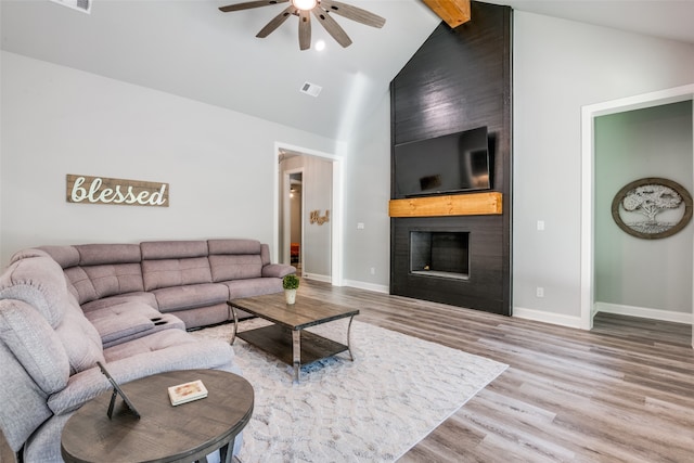 living room with hardwood / wood-style floors, high vaulted ceiling, ceiling fan, beamed ceiling, and a large fireplace