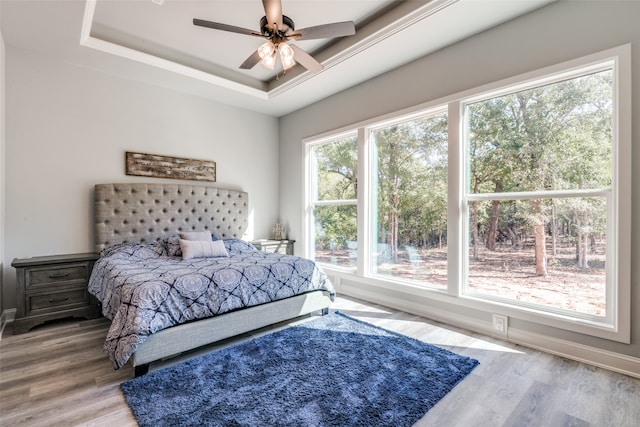 bedroom with hardwood / wood-style flooring, ceiling fan, and a tray ceiling