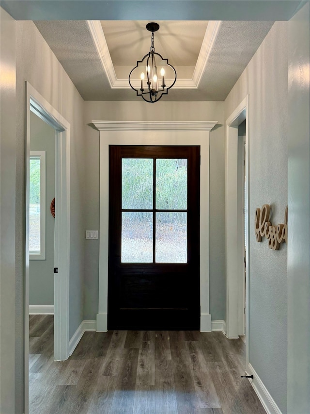 doorway to outside with hardwood / wood-style floors, an inviting chandelier, and a raised ceiling