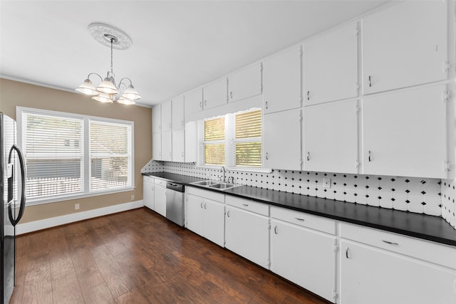 kitchen featuring appliances with stainless steel finishes, white cabinetry, decorative light fixtures, and tasteful backsplash