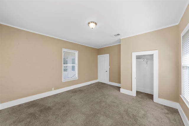 unfurnished bedroom with crown molding, a closet, and carpet flooring