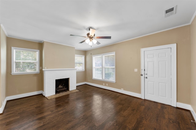 unfurnished living room featuring crown molding, a healthy amount of sunlight, dark hardwood / wood-style flooring, and a fireplace