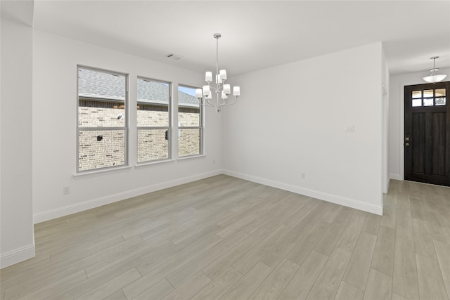 unfurnished dining area with a chandelier and light wood-type flooring