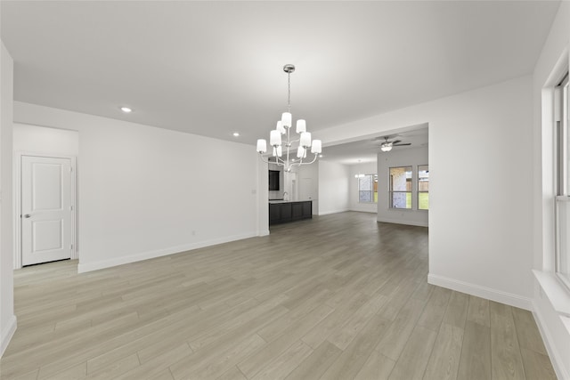 unfurnished living room with ceiling fan with notable chandelier and light hardwood / wood-style flooring