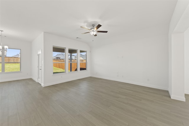 unfurnished living room with ceiling fan with notable chandelier and light hardwood / wood-style flooring