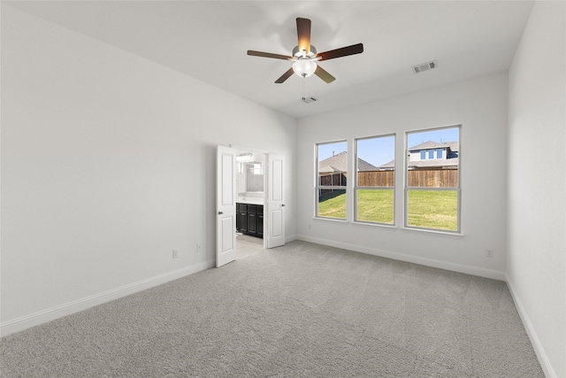 unfurnished bedroom featuring light colored carpet, ceiling fan, and ensuite bathroom