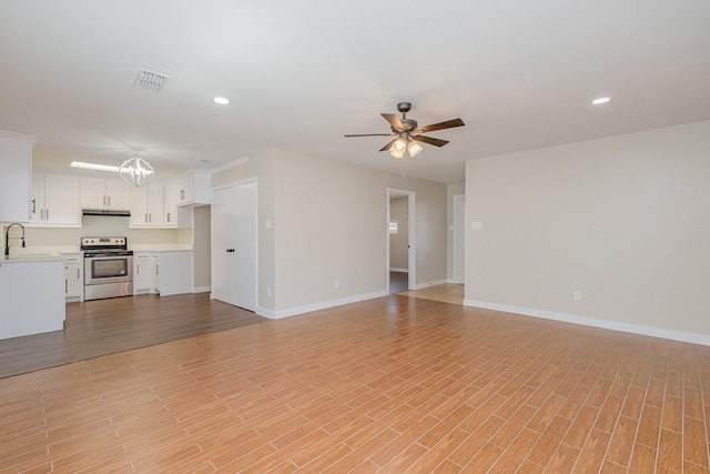 unfurnished living room featuring ceiling fan with notable chandelier, light hardwood / wood-style floors, and sink