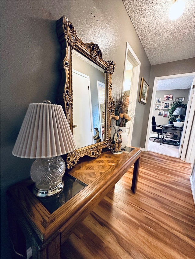 hall with a textured ceiling and hardwood / wood-style floors