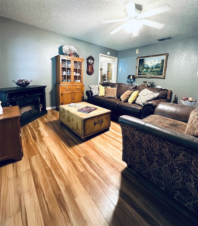 living room featuring a textured ceiling, hardwood / wood-style floors, and ceiling fan