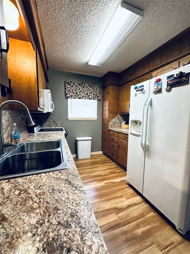 kitchen featuring a textured ceiling, light hardwood / wood-style floors, sink, and white appliances