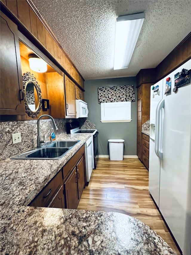 1402 Marie St N, Comanche, TX 76442 - kitchen with white appliances, a sink, a textured ceiling, decorative backsplash, and baseboards