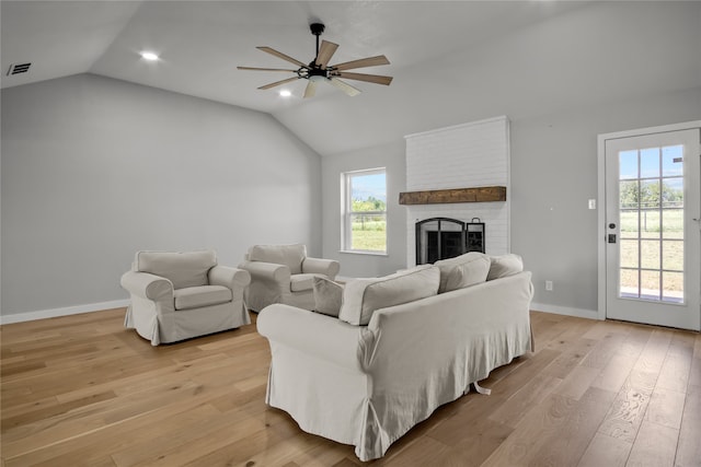 living room featuring light hardwood / wood-style floors, a wealth of natural light, ceiling fan, and a brick fireplace