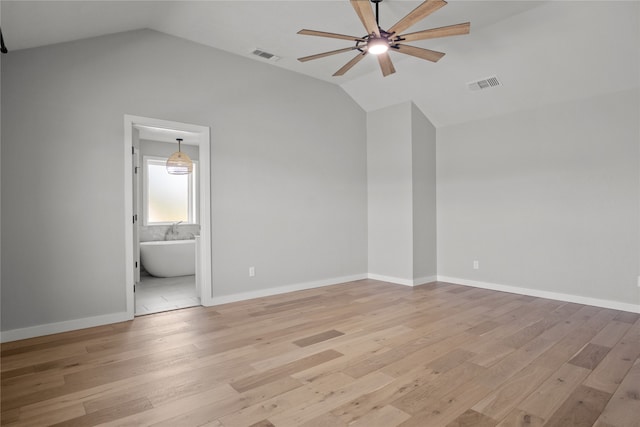 unfurnished bedroom featuring light wood-type flooring, vaulted ceiling, ensuite bath, and ceiling fan