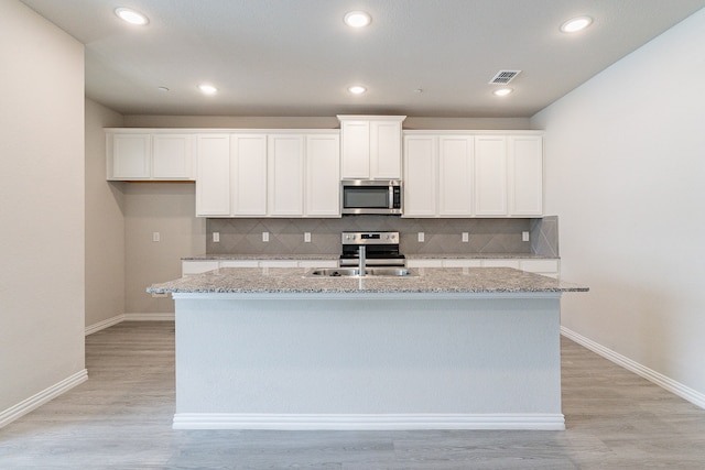 kitchen with white cabinets, appliances with stainless steel finishes, a kitchen island with sink, and sink