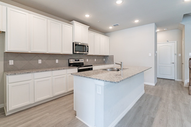 kitchen with light wood-type flooring, sink, white cabinets, a center island with sink, and appliances with stainless steel finishes