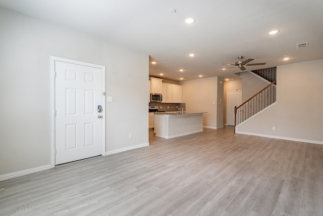 unfurnished living room featuring light hardwood / wood-style floors, ceiling fan, and sink