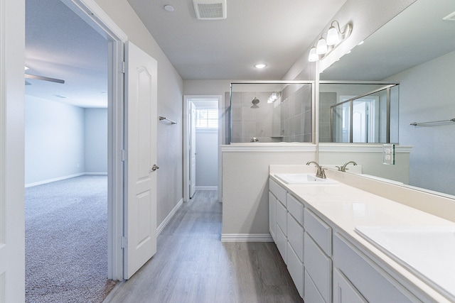 bathroom featuring walk in shower, wood-type flooring, vanity, and ceiling fan