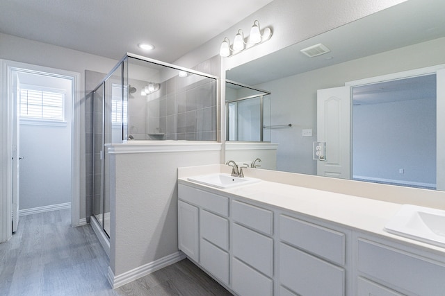 bathroom featuring wood-type flooring, a shower with door, and vanity