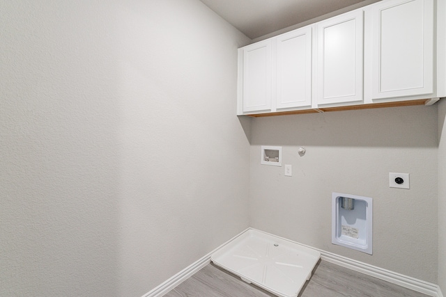 washroom featuring hookup for a washing machine, hookup for a gas dryer, light hardwood / wood-style flooring, electric dryer hookup, and cabinets