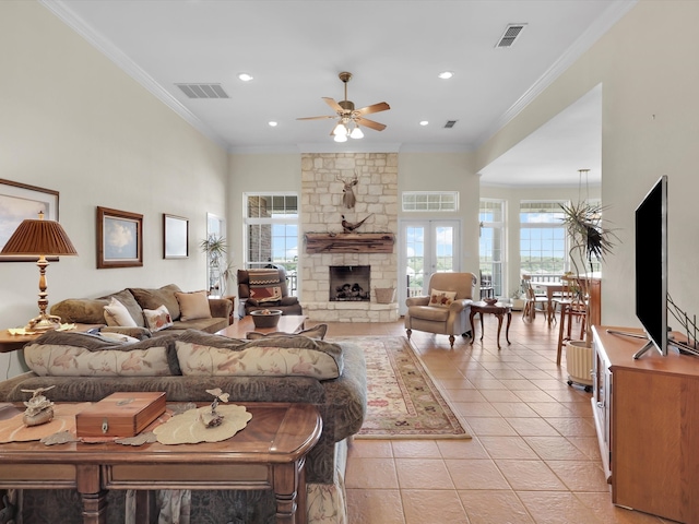 living room with light tile patterned flooring, ornamental molding, a wealth of natural light, and a stone fireplace