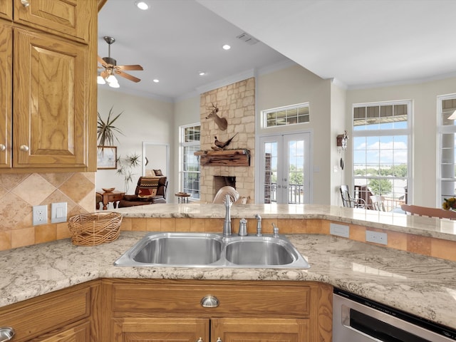 kitchen with tasteful backsplash, sink, a stone fireplace, kitchen peninsula, and ornamental molding