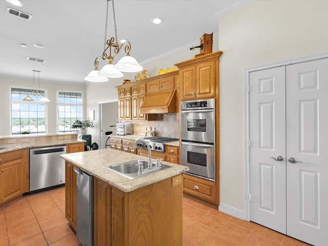 kitchen featuring tasteful backsplash, appliances with stainless steel finishes, decorative light fixtures, light tile patterned floors, and a kitchen island with sink