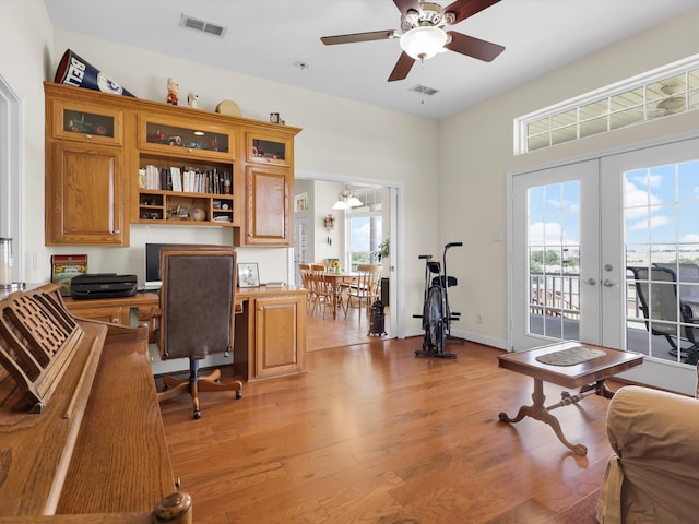 office space with french doors, ceiling fan, a healthy amount of sunlight, and light hardwood / wood-style flooring