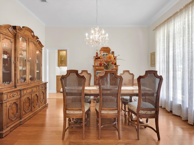 dining space with light hardwood / wood-style floors, a notable chandelier, and ornamental molding