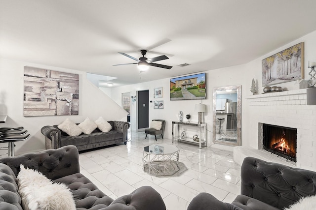 living area with ceiling fan, marble finish floor, a brick fireplace, and visible vents