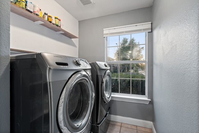 clothes washing area featuring washer and dryer and light tile patterned floors