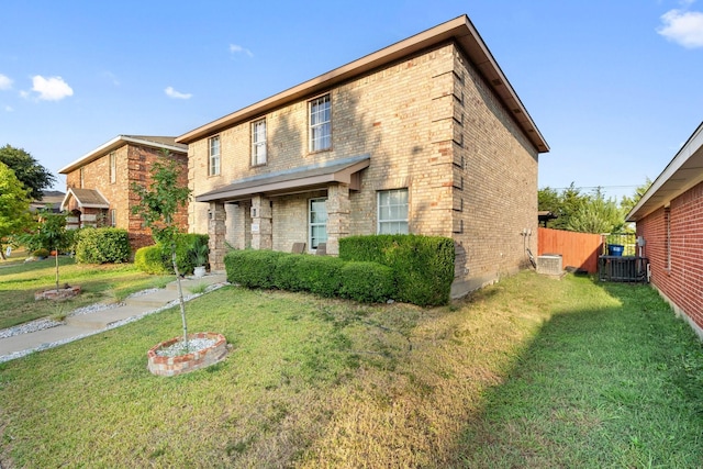 view of front of property featuring a front yard, brick siding, fence, and central AC unit