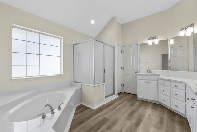 bathroom featuring hardwood / wood-style floors, vaulted ceiling, vanity, and separate shower and tub