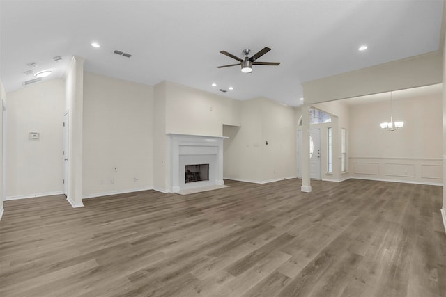 unfurnished living room with ceiling fan with notable chandelier and wood-type flooring