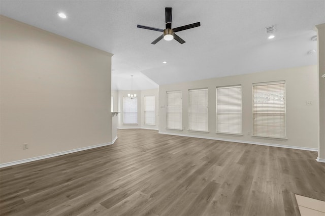 unfurnished living room with hardwood / wood-style flooring, ceiling fan with notable chandelier, and a healthy amount of sunlight