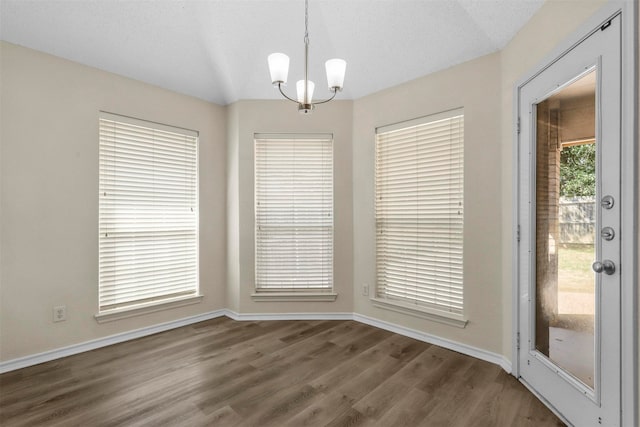 unfurnished dining area with a textured ceiling, dark hardwood / wood-style floors, and a chandelier