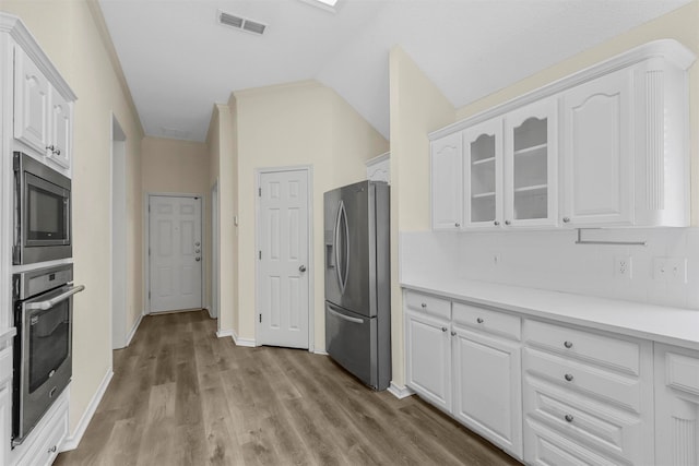 kitchen with light hardwood / wood-style flooring, stainless steel appliances, lofted ceiling, and white cabinetry